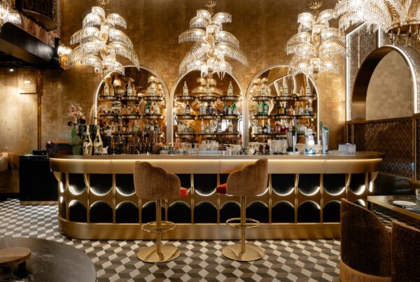 Gaucho Helsinki bar with gold-toned finishes, illuminated arched bottle displays, sculptural chandeliers and patterned flooring.